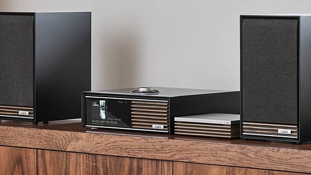 Black audio speakers and a receiver on a wooden surface.
