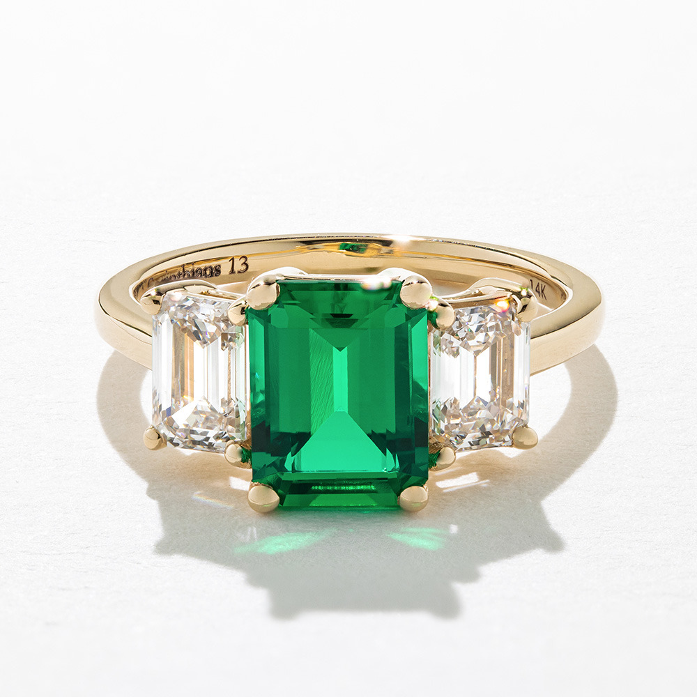 stunning 3 stone emerald engagement ring with lab grown diamond side stones and lab created emerald center stone in 14k yellow gold