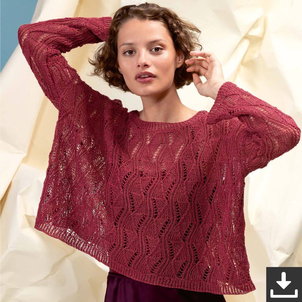 Eine Frau, die einen burgunderroten Strickpullover mit lockerer Passform und Ajourmuster trägt.
