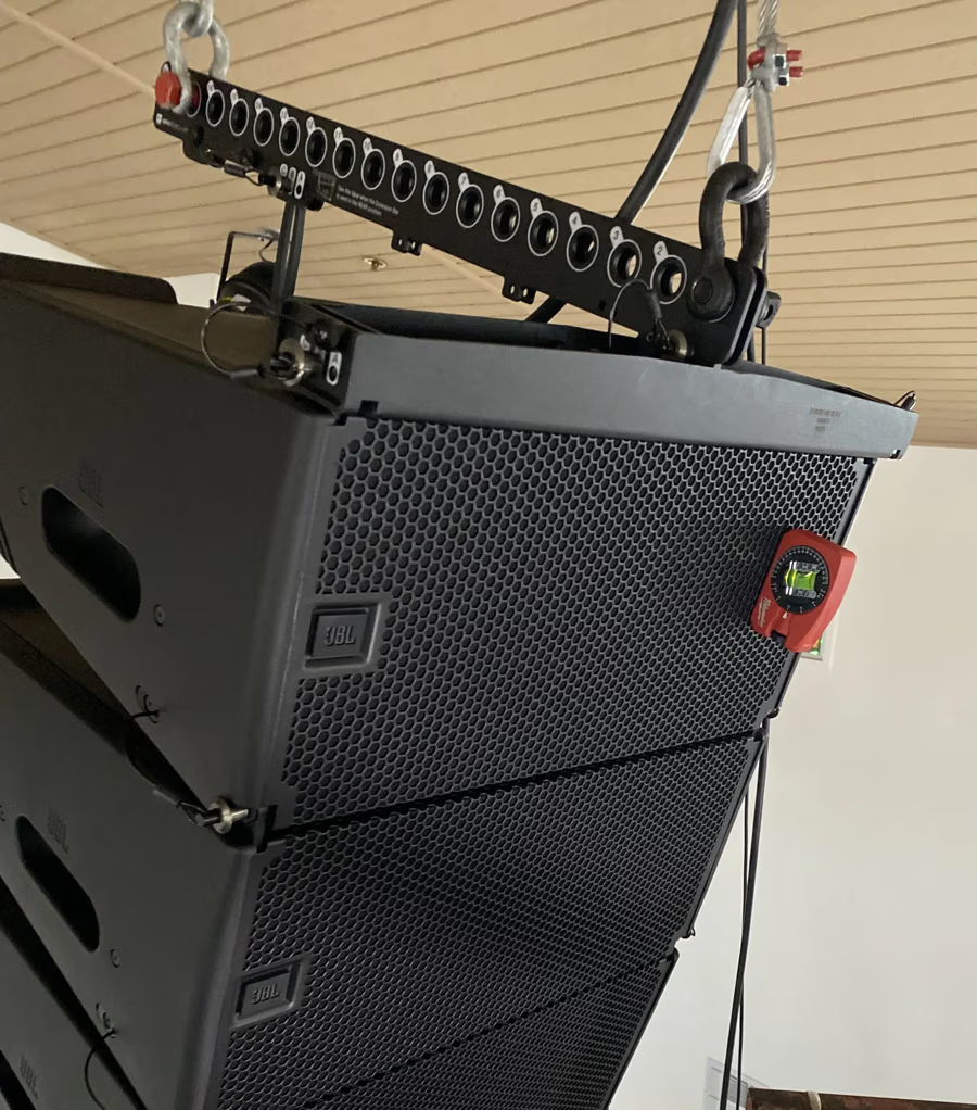 Stacked black speakers suspended from the ceiling with connectors visible.