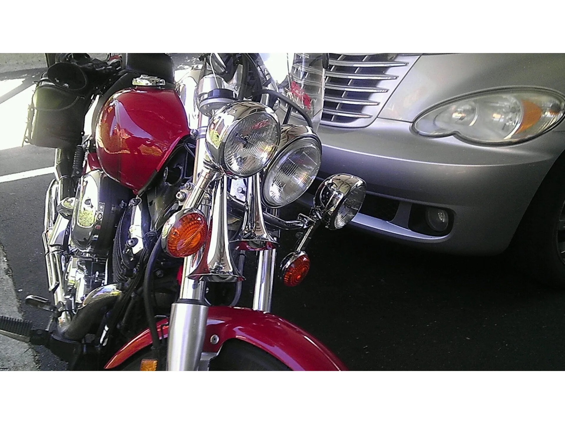 Low-angle front-quarter Ty's red Yamaha V-Star motorcycle chrome PsychoBlasters V2 horns vertically between forks below chrome headlights next to amber turn signals polished triple-tree customer install gallery photo 2