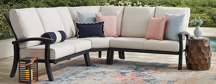 Outdoor sectional sofa with cushions and decorative pillows on a patterned rug.