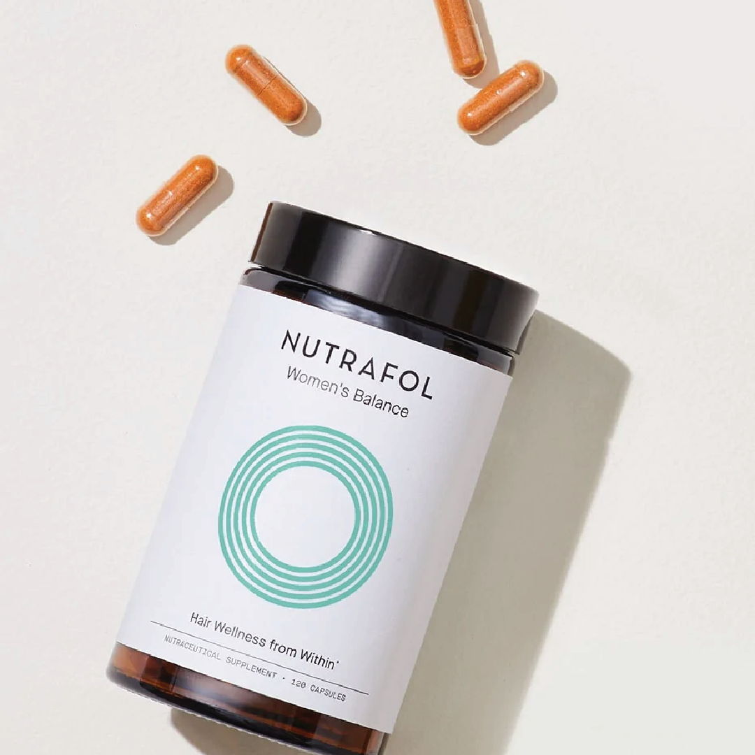 Nutrafol women's hair supplement bottle with capsules on a light background.