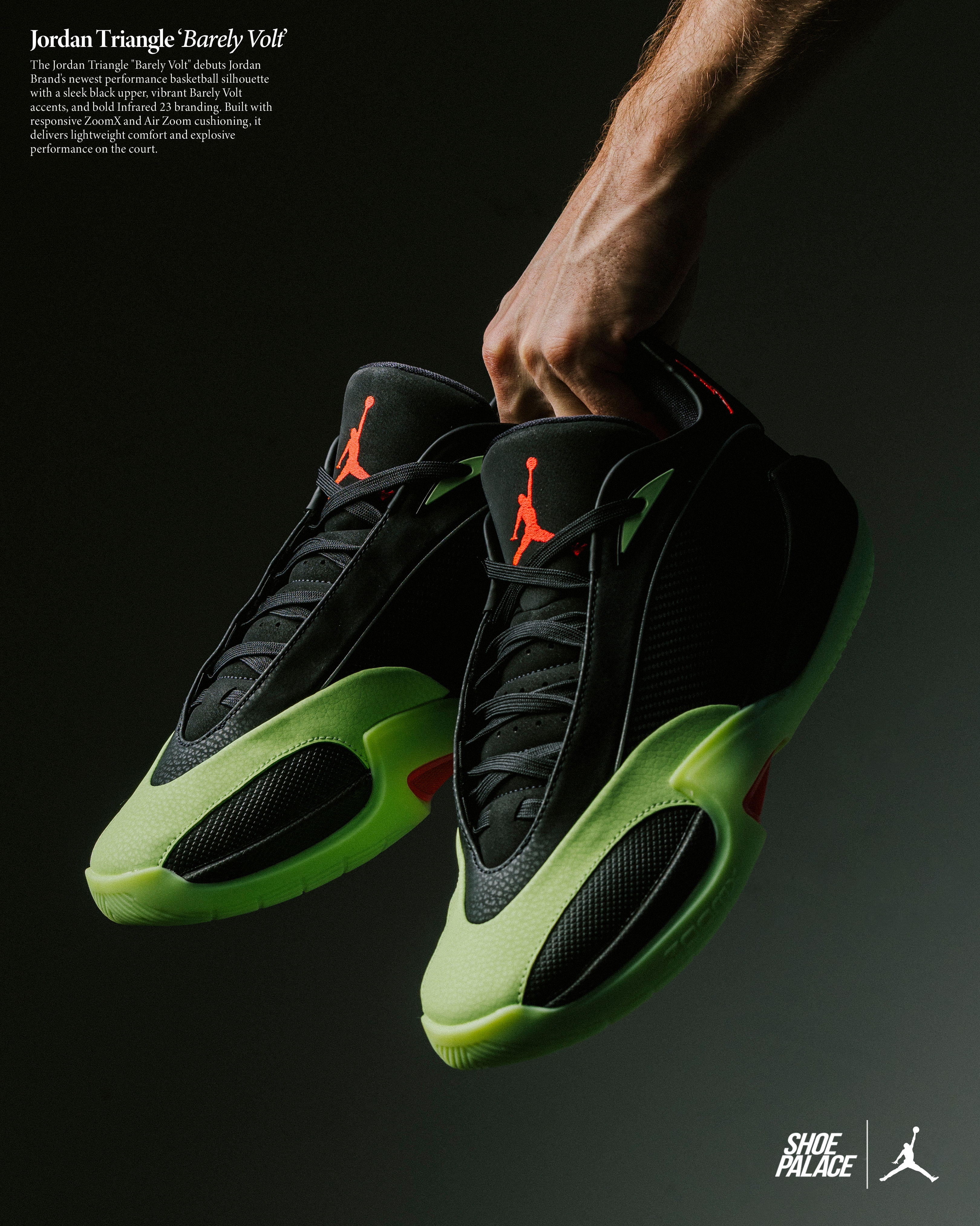A hand holding black and green Jordan sneakers on a dark background.