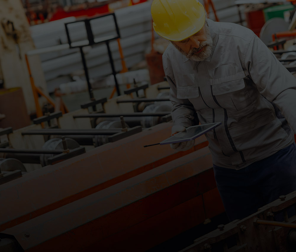 Worker in a manufacturing facility inspecting equipment, representing security and monitoring solutions for industrial and warehouse operations
