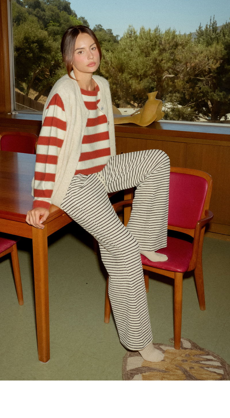 A person in striped clothing sitting on a chair by a table.