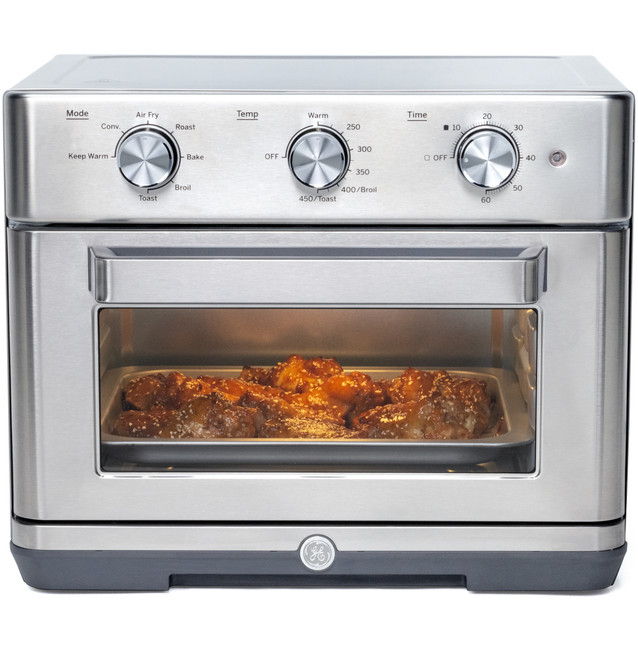 Stainless steel countertop oven with visible food inside.