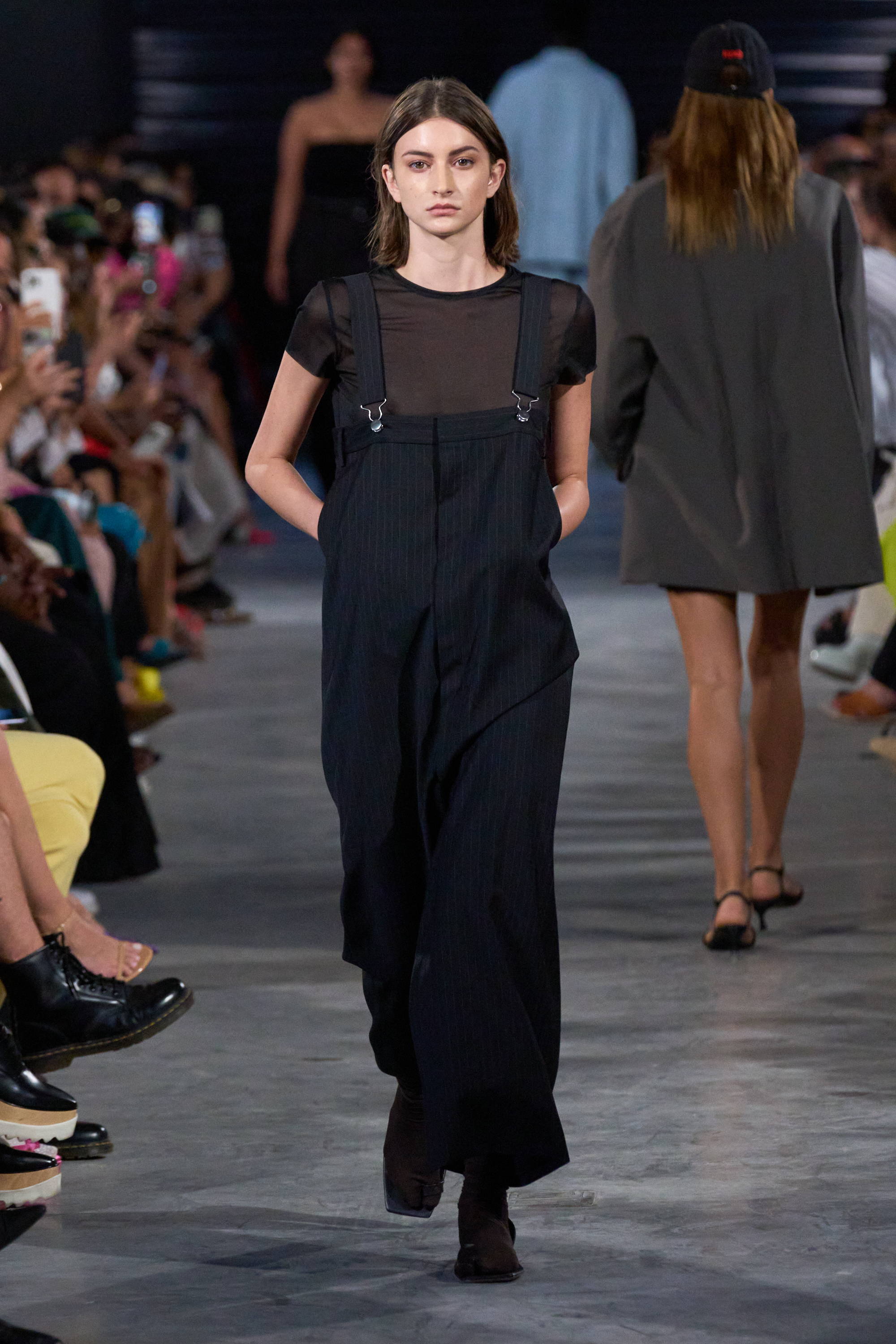 Model on a runway wearing pinstripe overalls