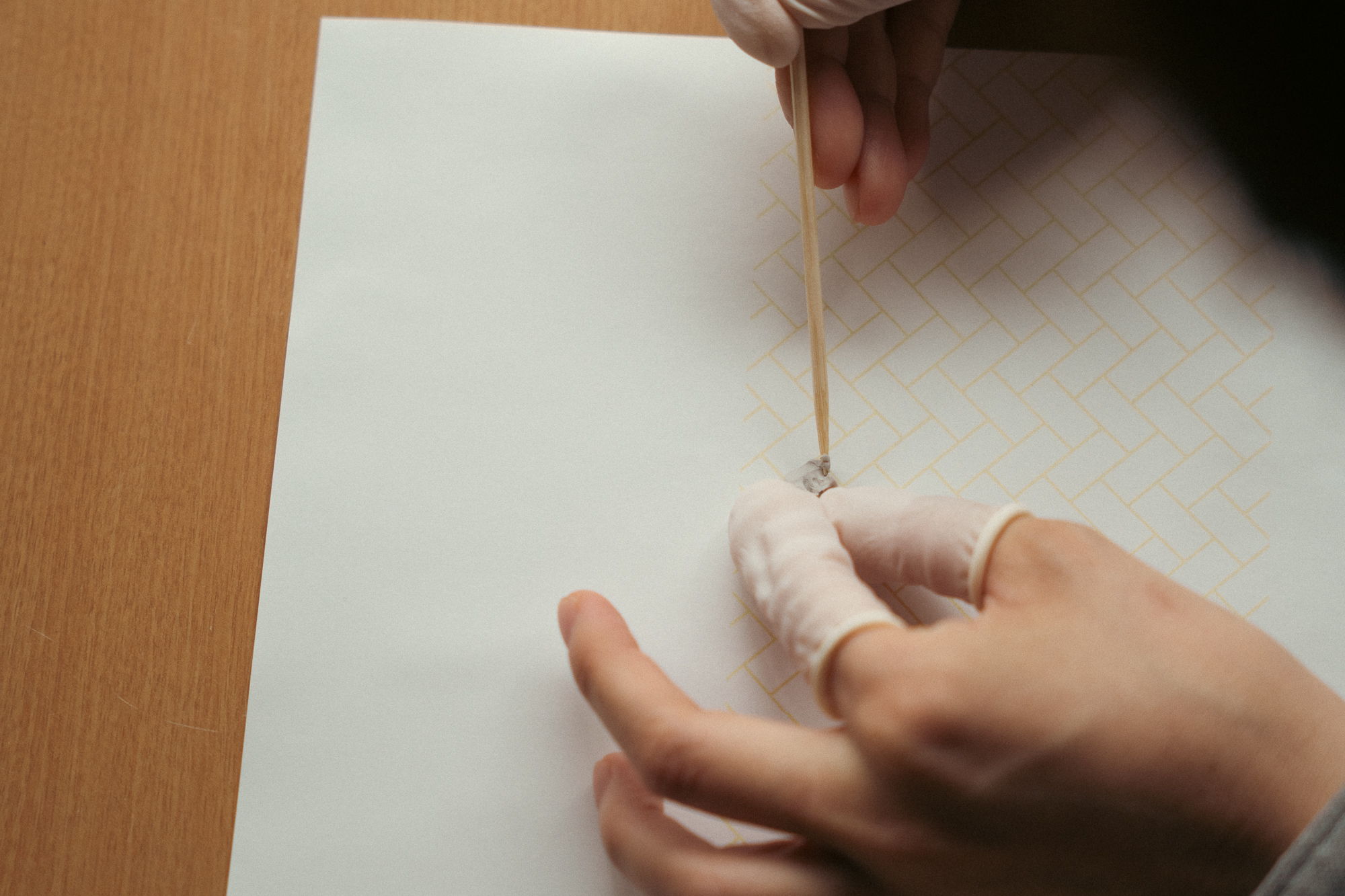 Person using a stick to apply something on paper.