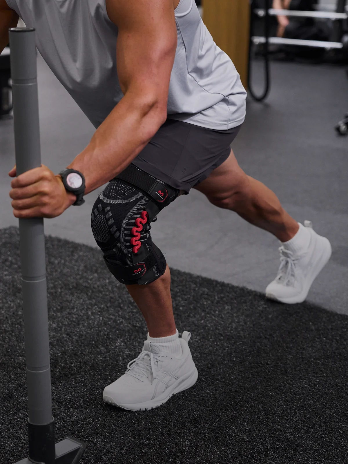 Person exercising with a resistance pole, wearing athletic gear and a knee sleeve.