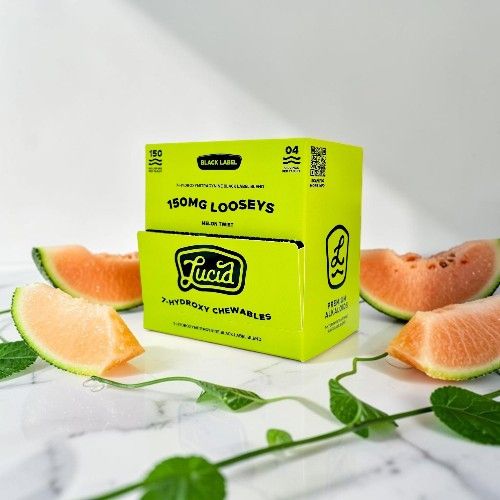 Bright yellow box of gummies surrounded by cantaloupe slices on a marble surface.