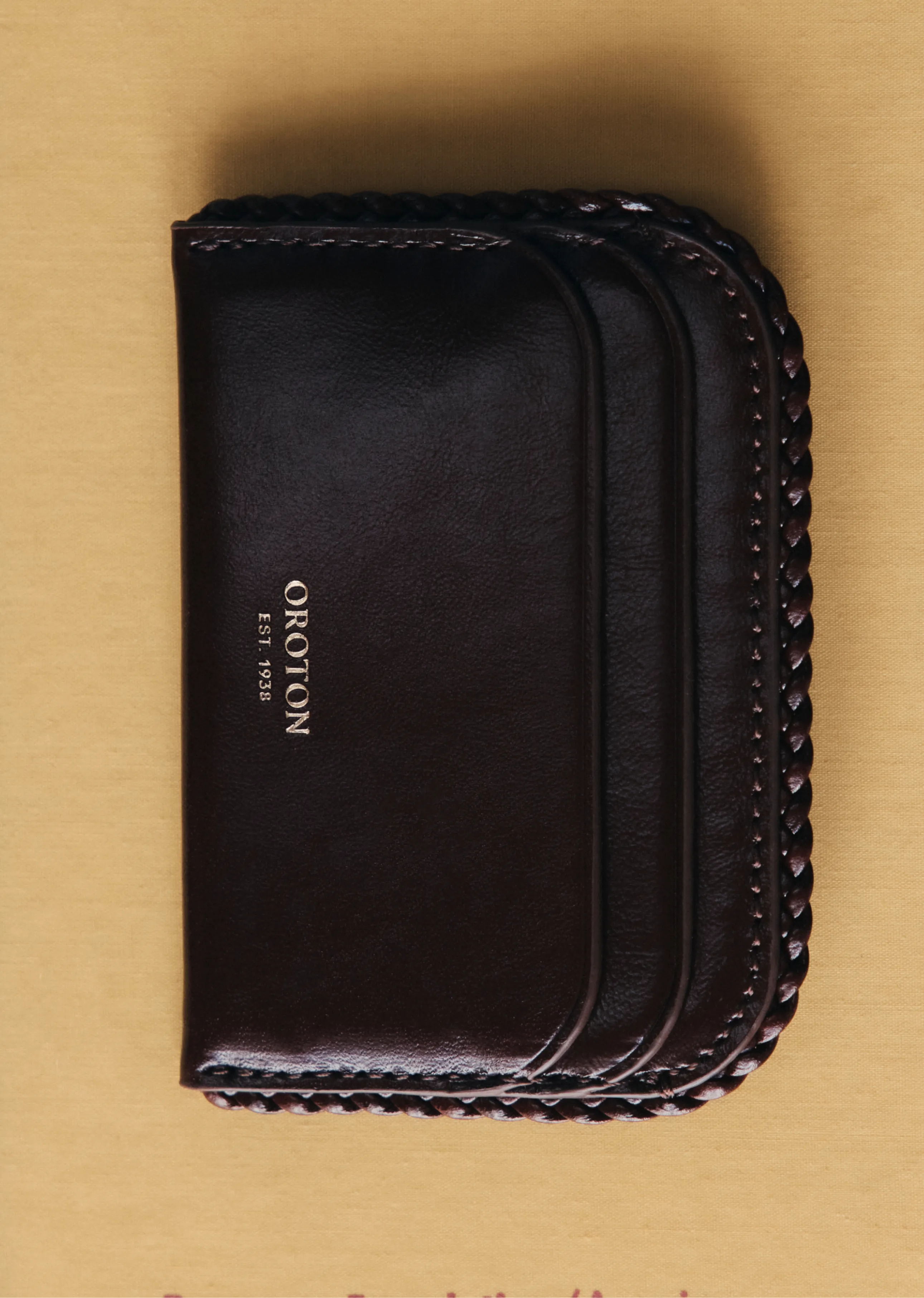 A dark leather wallet with a braided edge design.