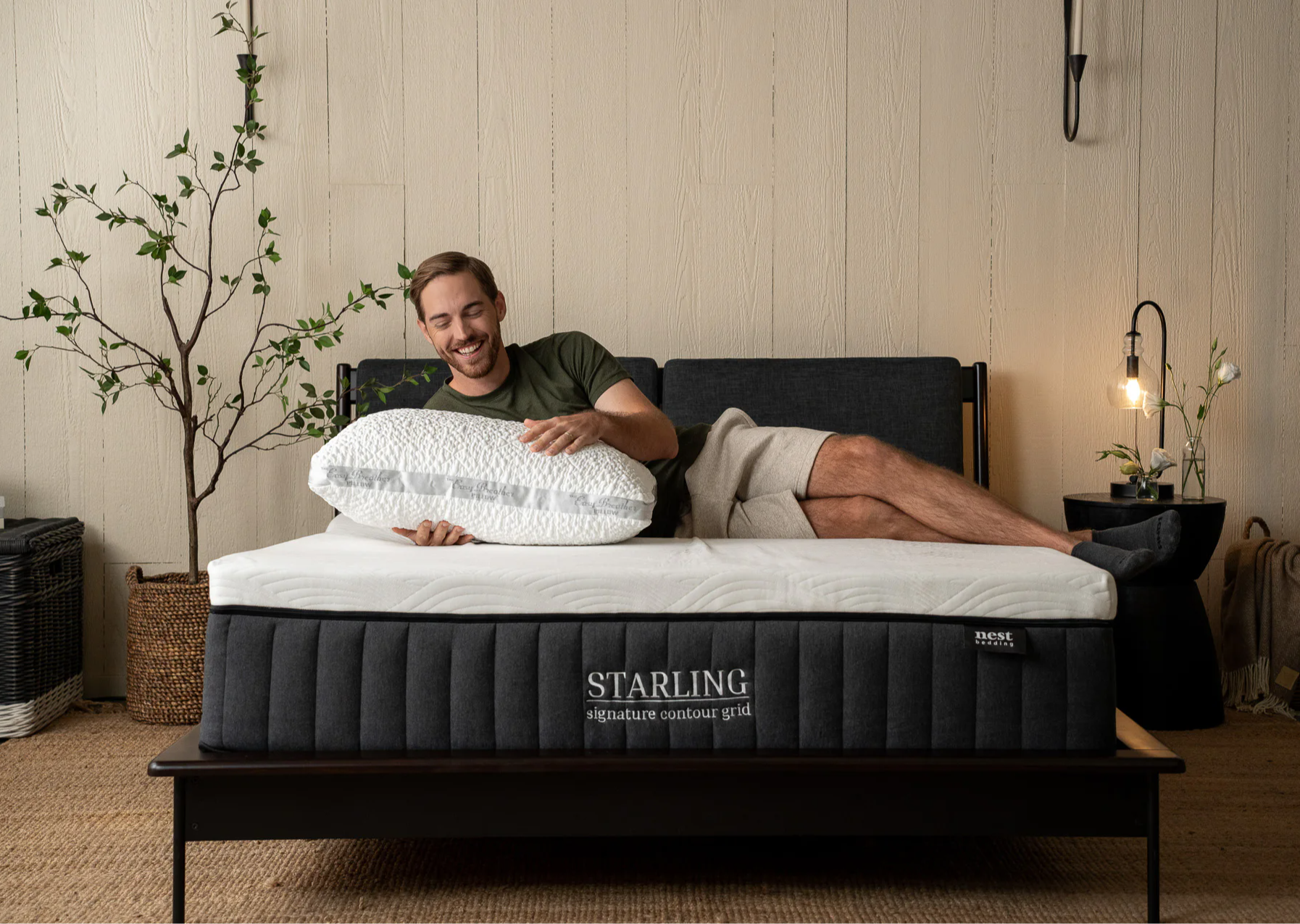 A man laying on a starling signature contour grid mattress holding an easy breather pillow