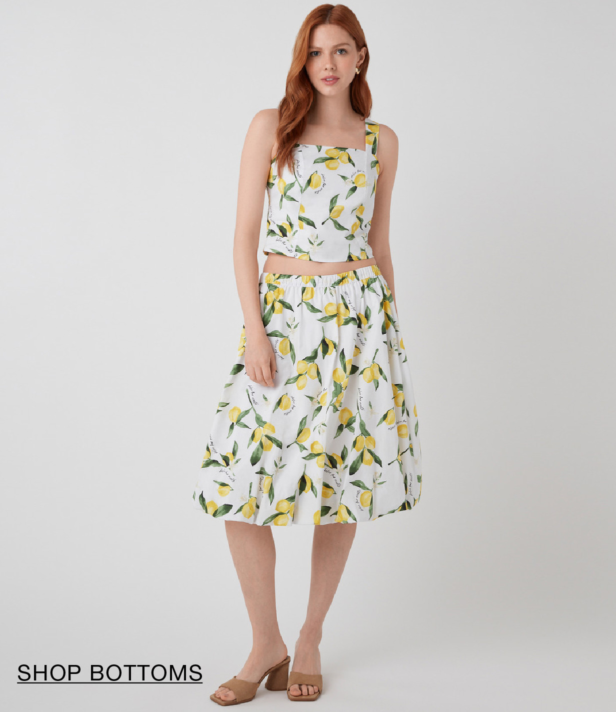 Woman in floral dress with a belt, standing on a light background.