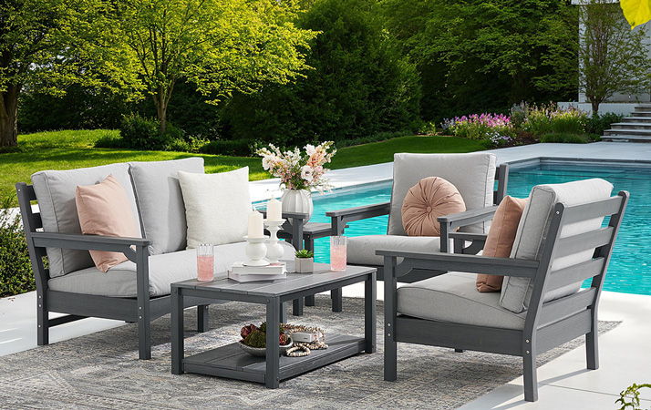 Outdoor seating area with gray furniture by a swimming pool.