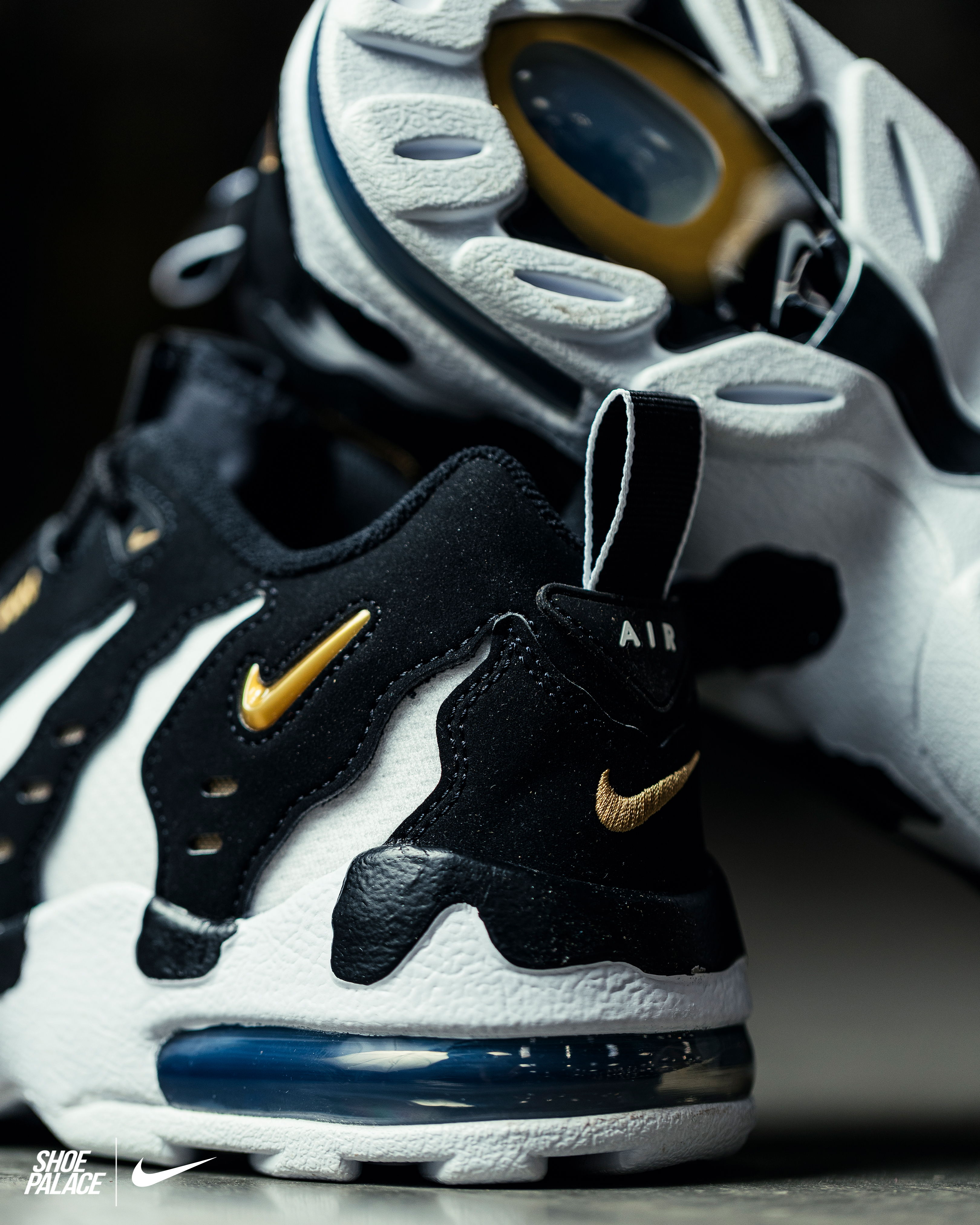 Black and white Nike Air shoes with gold accents.