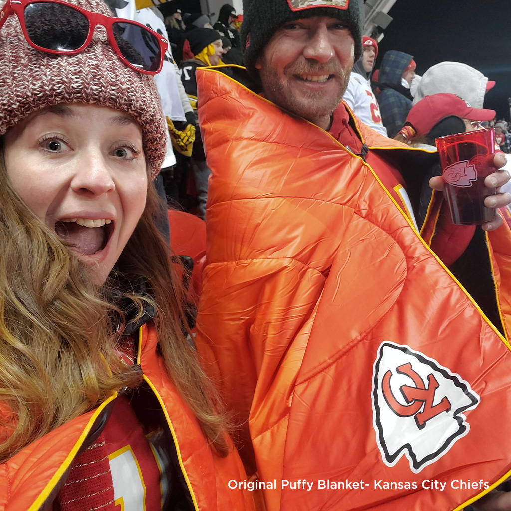 Two people wearing Kansas City Chiefs Rumpl blanket in stadium