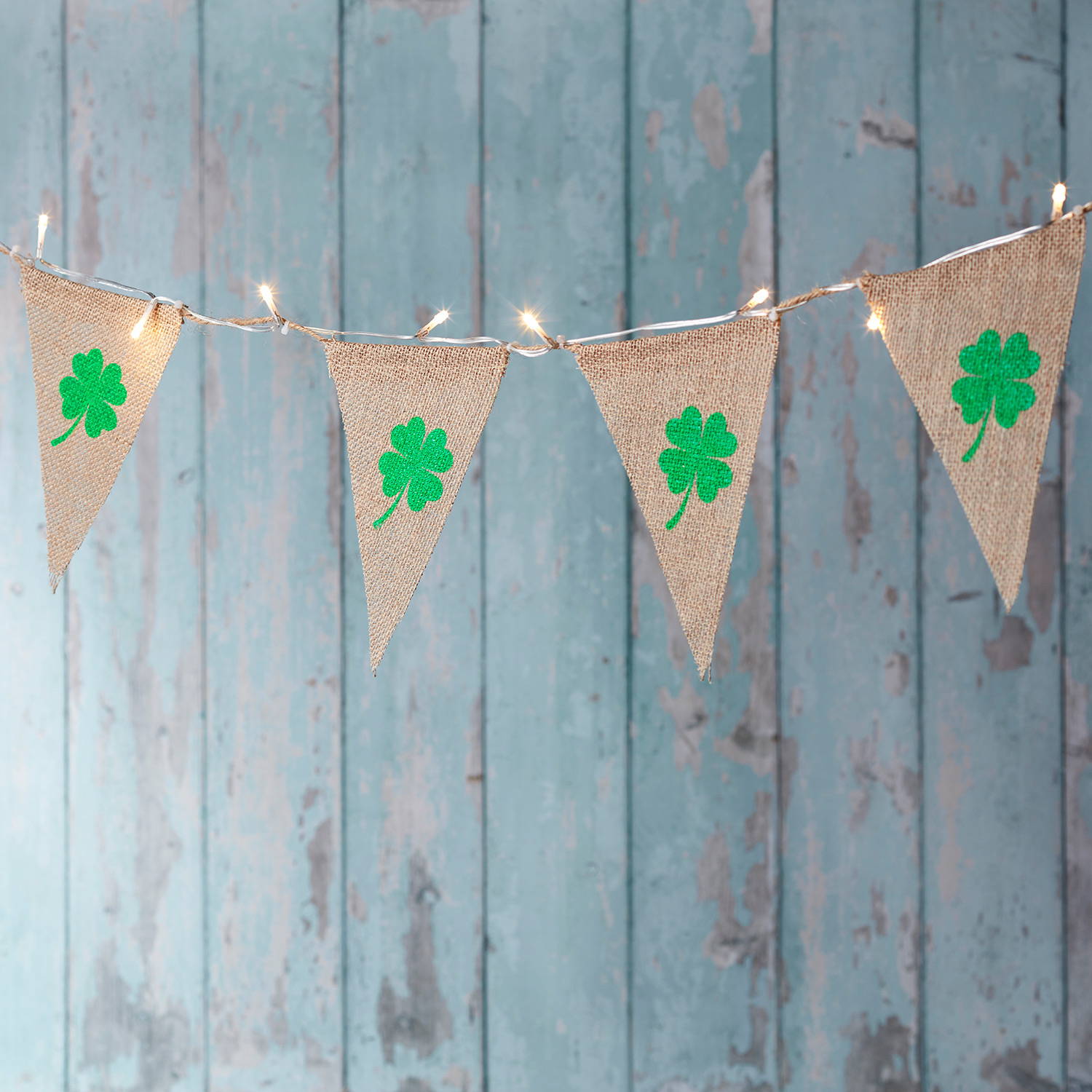 Shamrock LED hessian bunting decoration hanging in front of a blue rustic wooden wall.