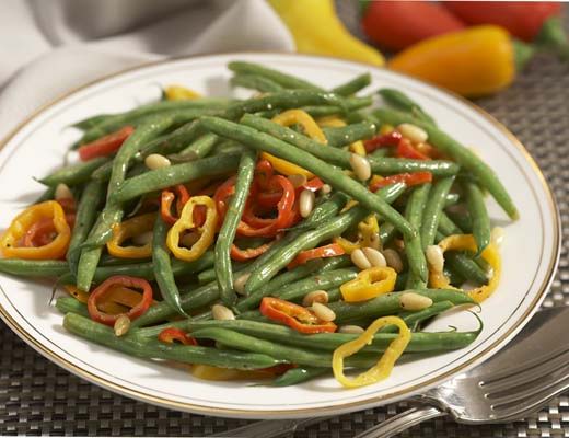 A plate of green beans with colorful peppers and peanuts.
