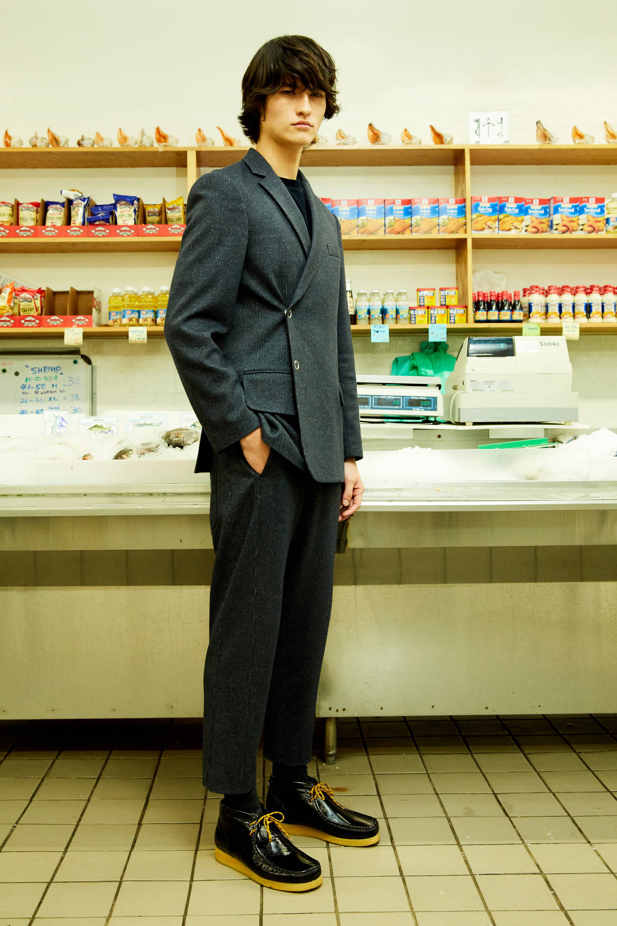 A person in a suit stands in a store aisle.