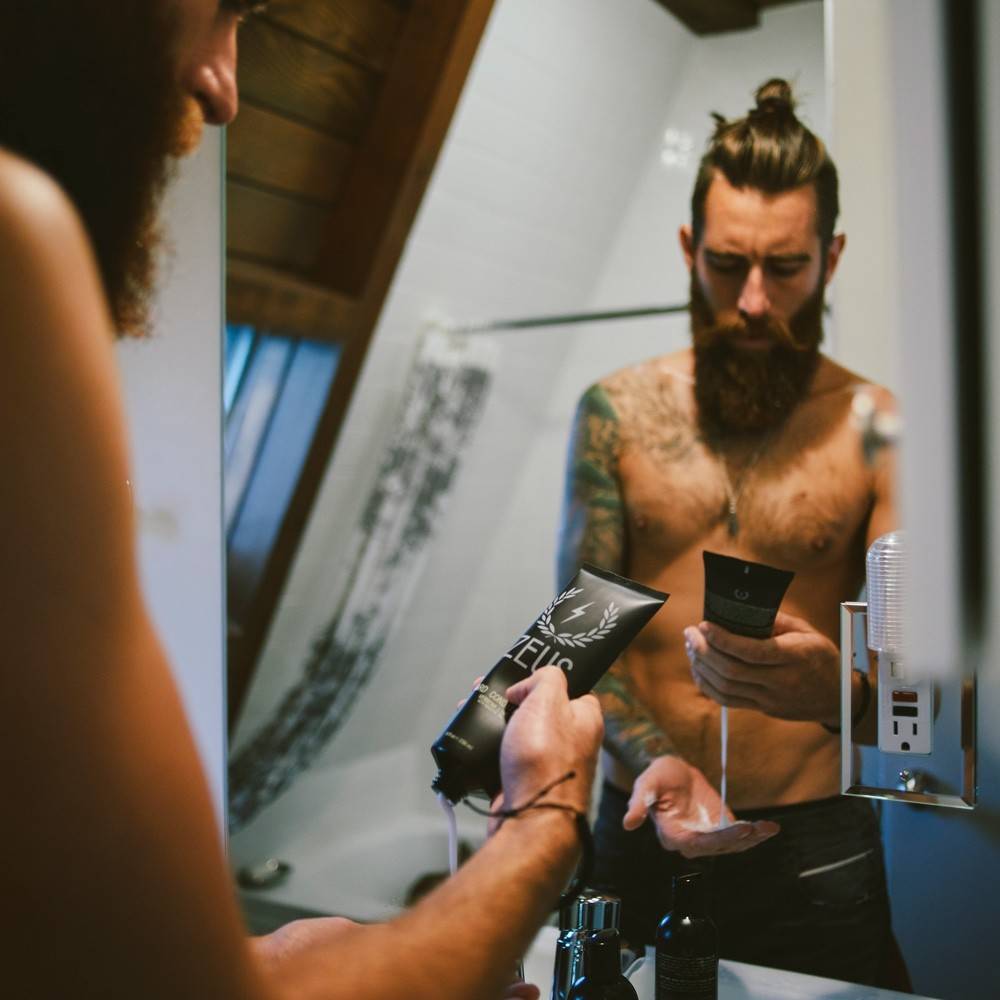 man dispensing zeus beard conditioner onto palm