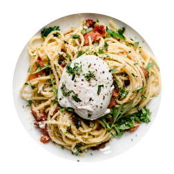 spaghetti pasta with greens and tomatoes topped with a cooked egg