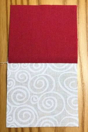 Closeup of 2.5 inch square dark red fabric square pieced to a 2.5 inch square light fabric square