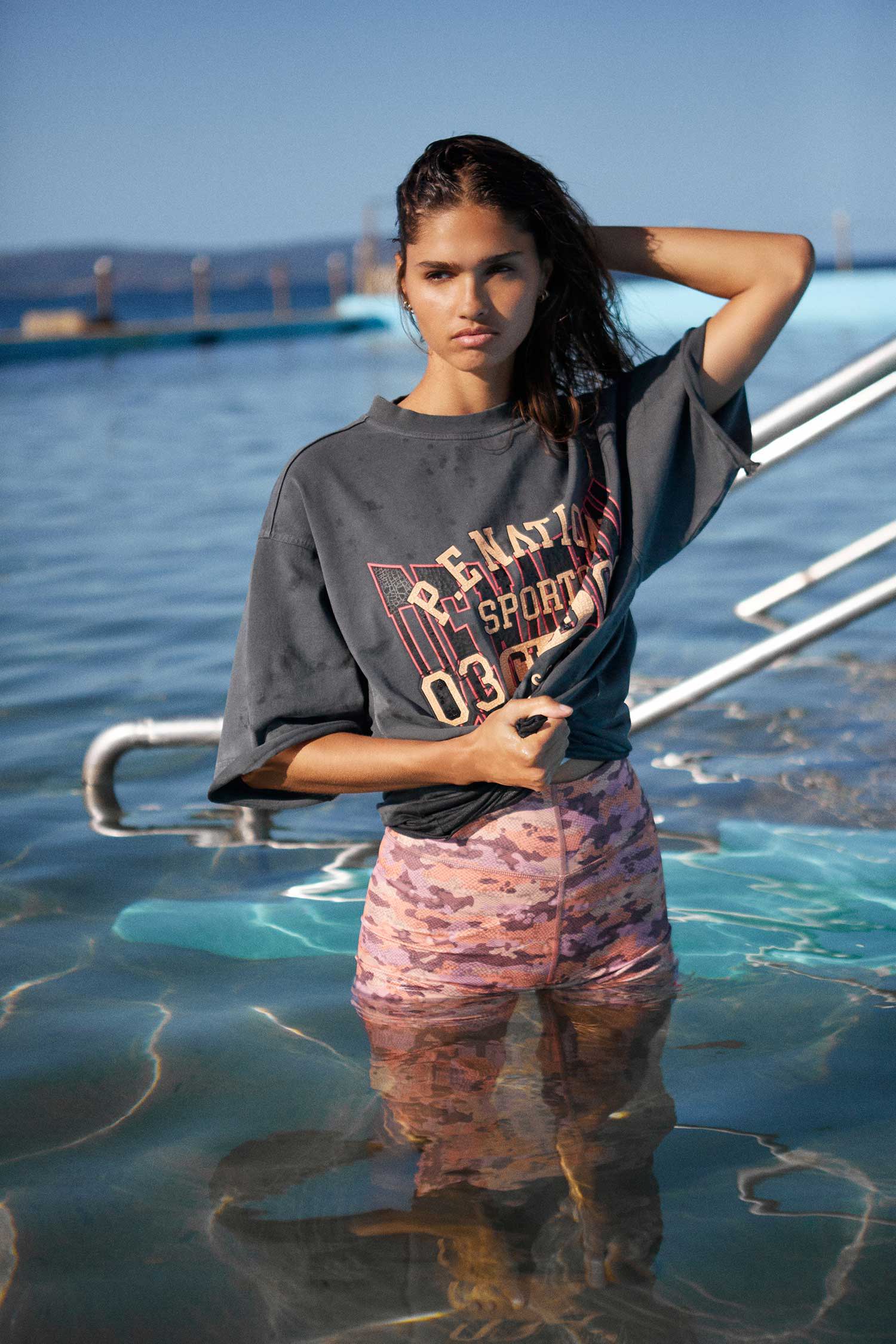 Girl standing in an ocean pool, wearing T-shirt and shorts