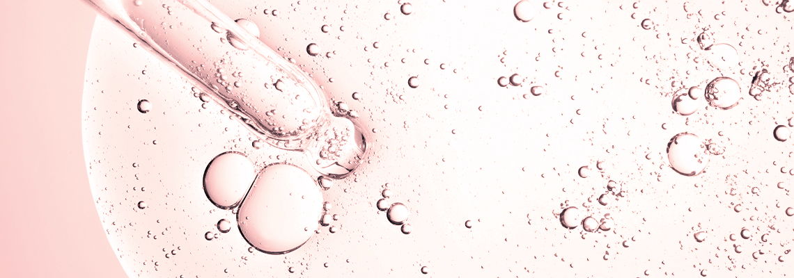 Pipette over bubbles in a light pink liquid background.