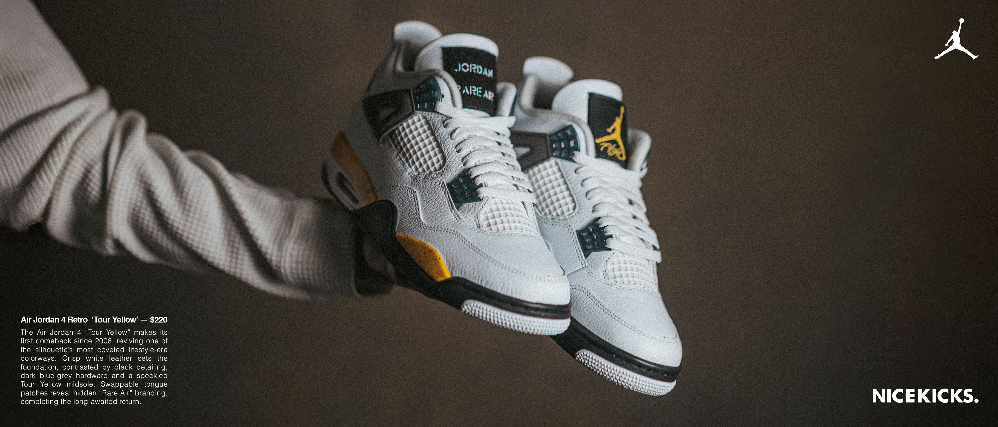 A person holding white and yellow Air Jordan 4 sneakers.