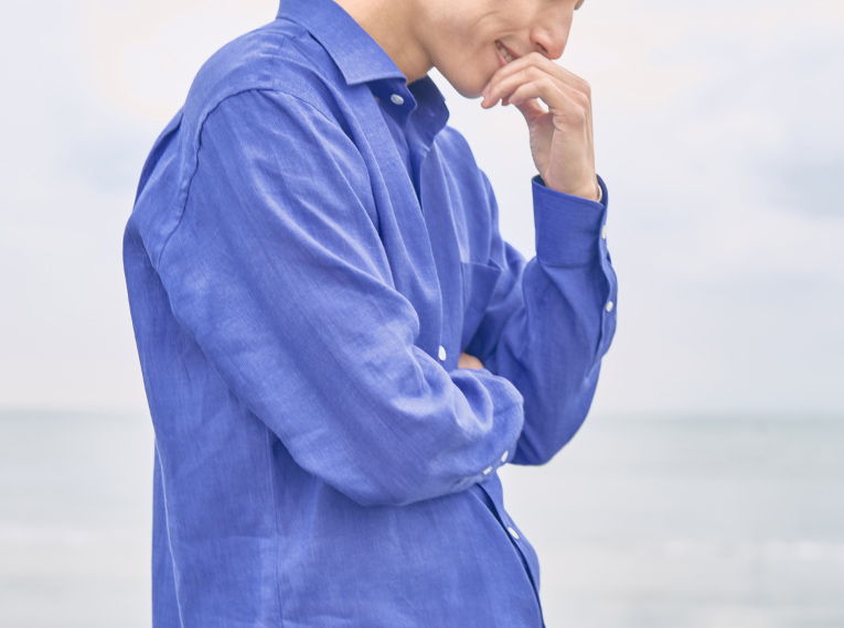 Person in a blue shirt thinking by the seaside.