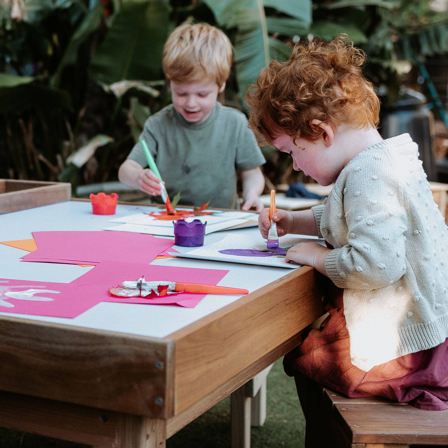 Children Expressing Their Creativity by Painting on an Art Table with Paint Brushes