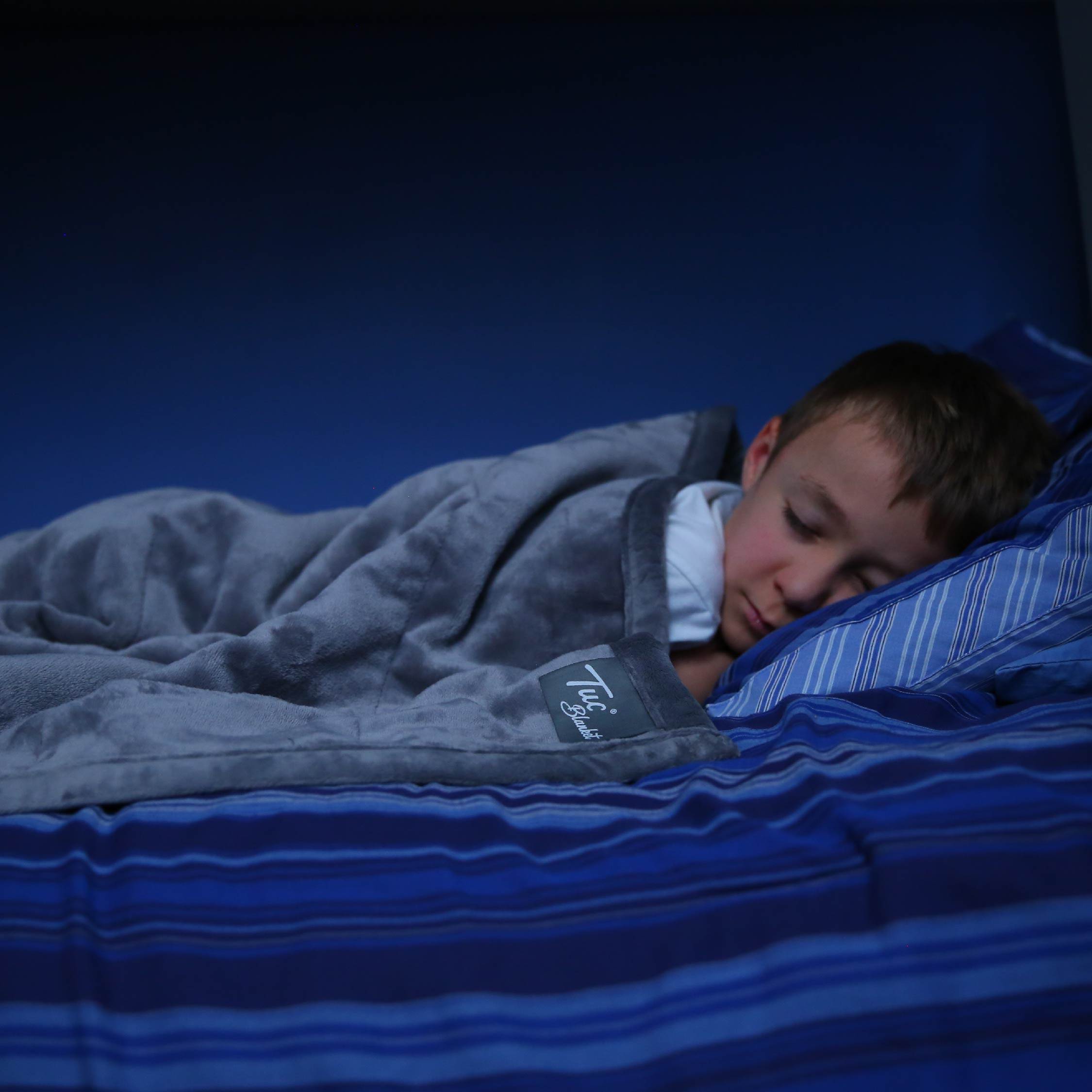 Boy sleeping peacefully with the Tuc Kids Warm Weighted Blanket.