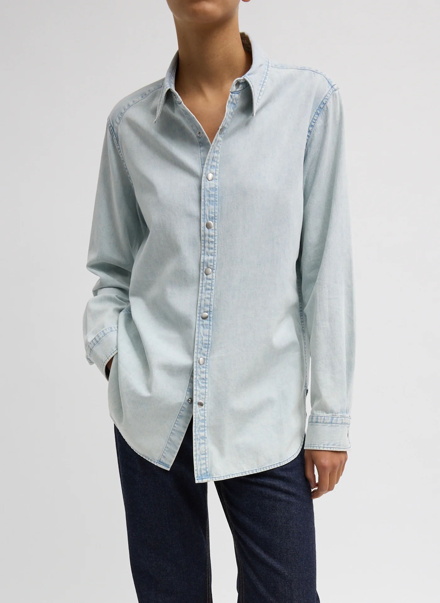 A person wearing a light blue button-up shirt and dark pants.