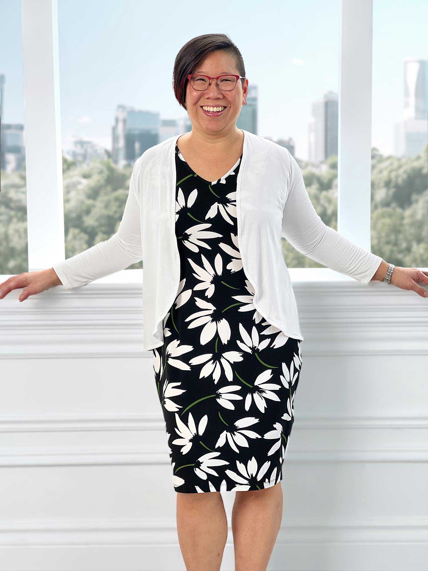 Woman standing wearing Miik's Wesley cropped cardigan in white over a dress