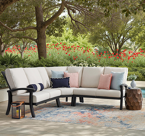 Outdoor seating area with a sectional couch and decorative pillows.