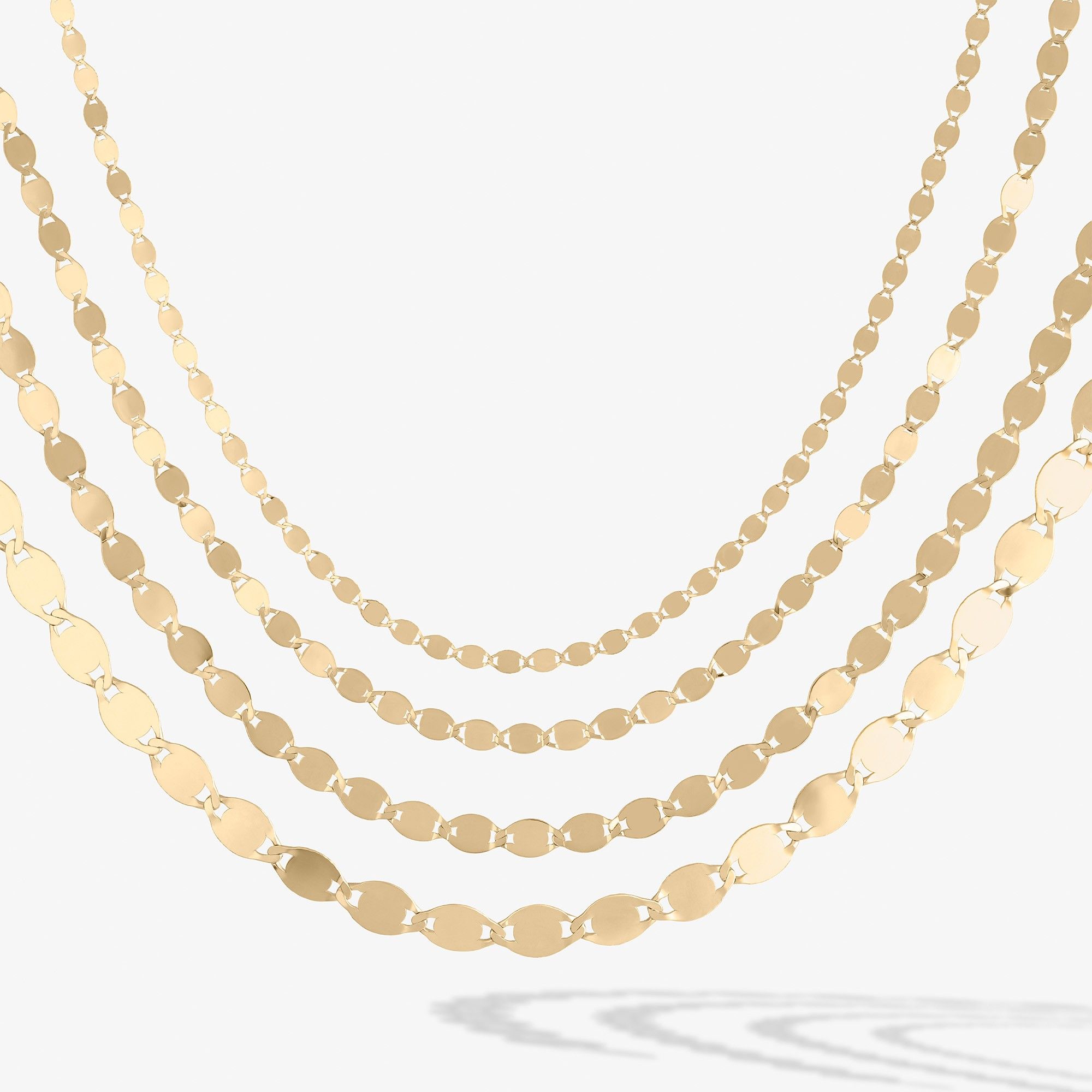 Gold layered necklaces with circular and oval shapes on a white background.