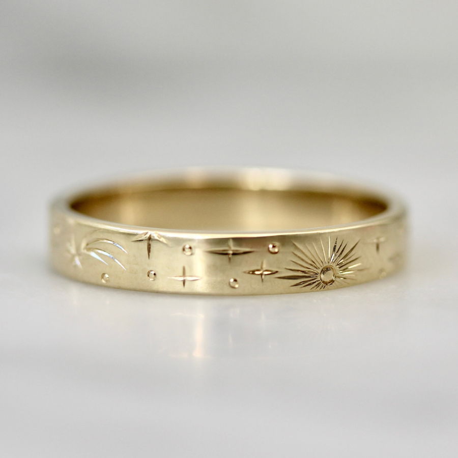 Hand engraved wedding band with stars, sun rays, and planets