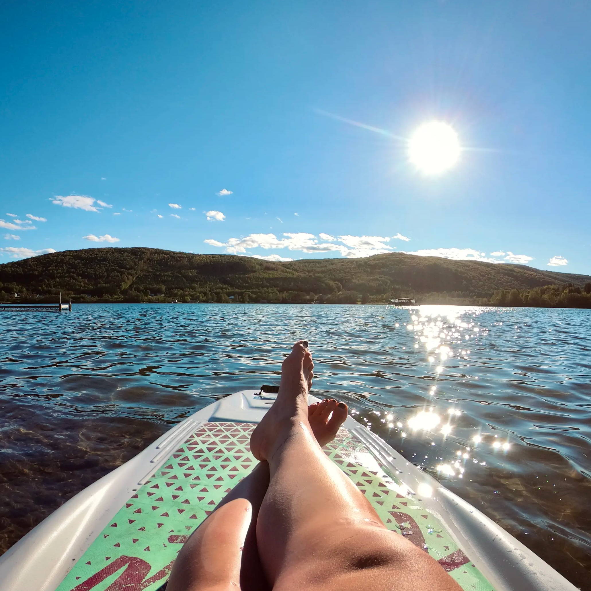 a person's legs on a paddle board in the water