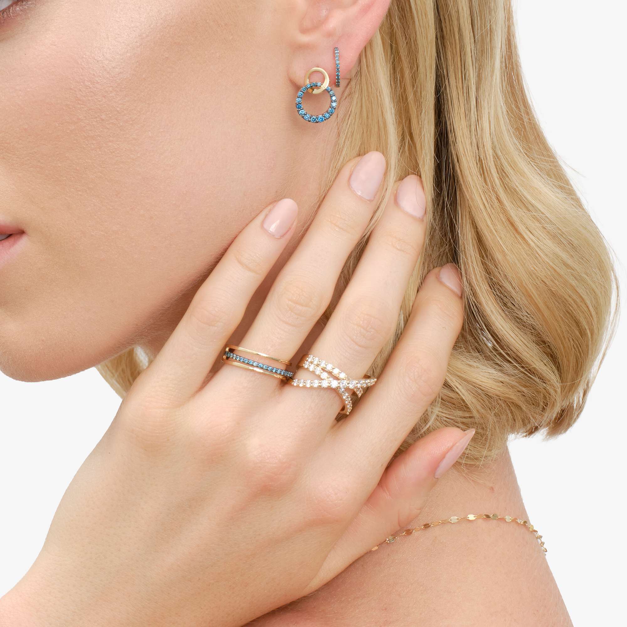 Model showcasing jewelry, including earrings and rings, with a focus on hands.