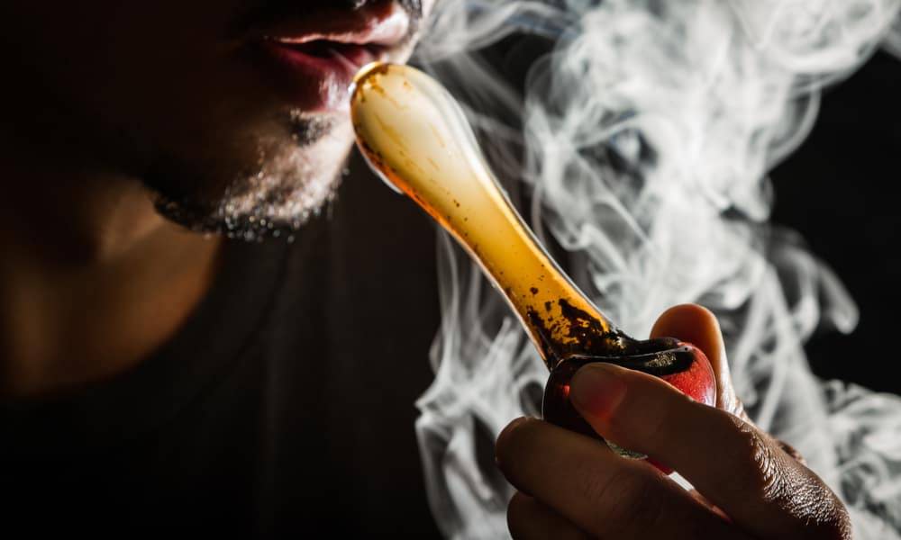 homem a fumar de cachimbo de mão de vidro