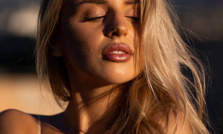 Young woman with long blonde hair, softly illuminated in natural light.