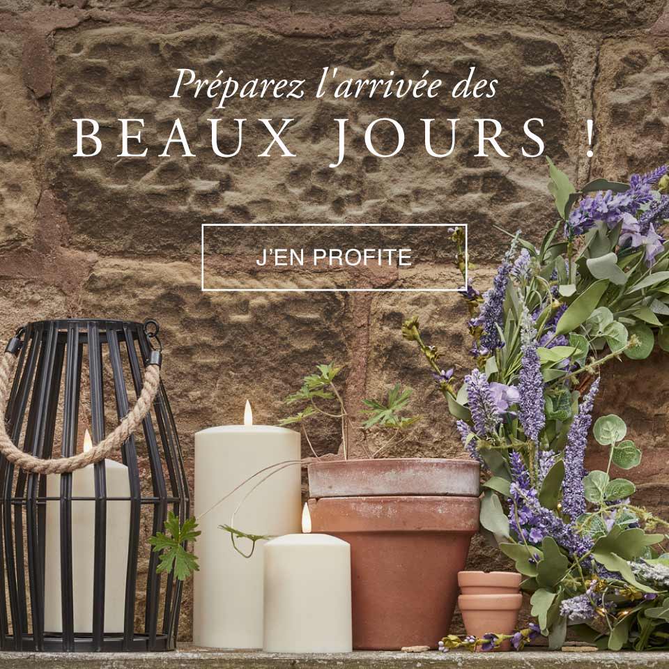 Lanterne d'extérieur avec des bougies d'extérieur et une couronne de fleur printanière posées dans le jardin. 