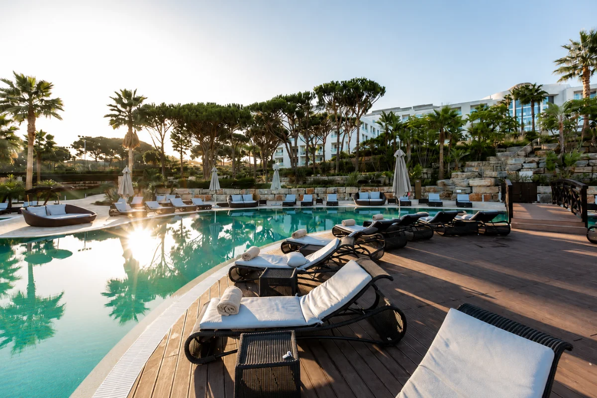 Luxury hotel pool with commercial chaise lounges, side tables, umbrellas, and comfortable outdoor lounge seating