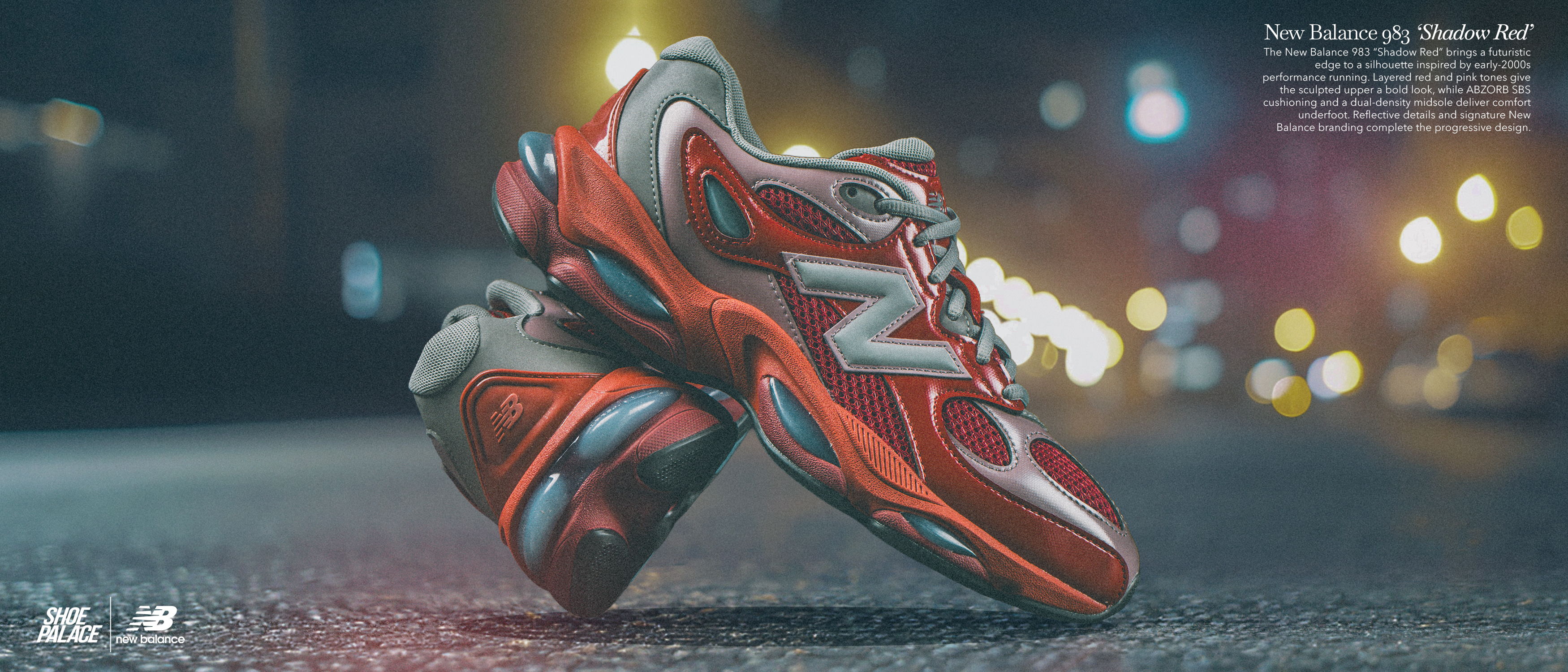 Red New Balance sneakers on a street with blurred city lights in the background.