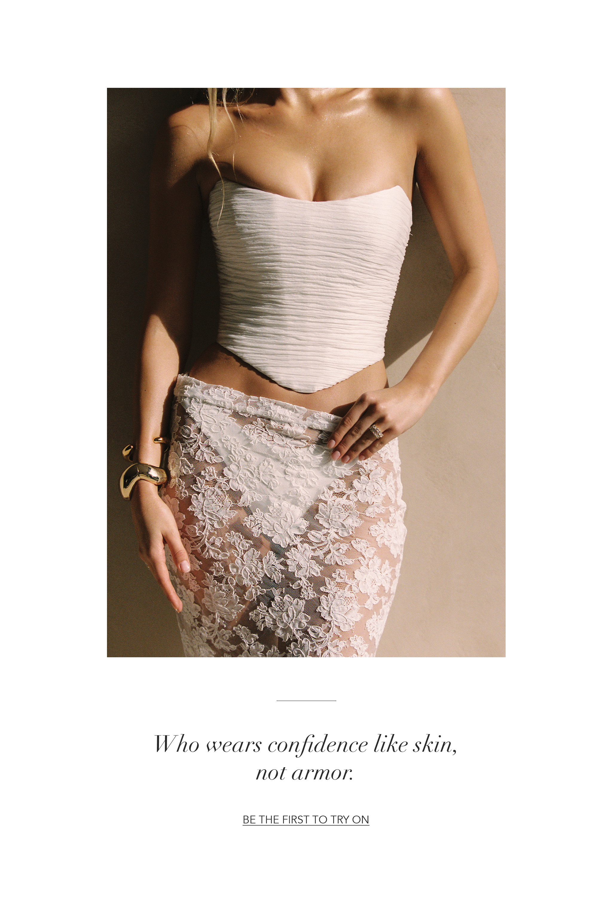 Woman in a fitted top and lace skirt, standing against a neutral background.