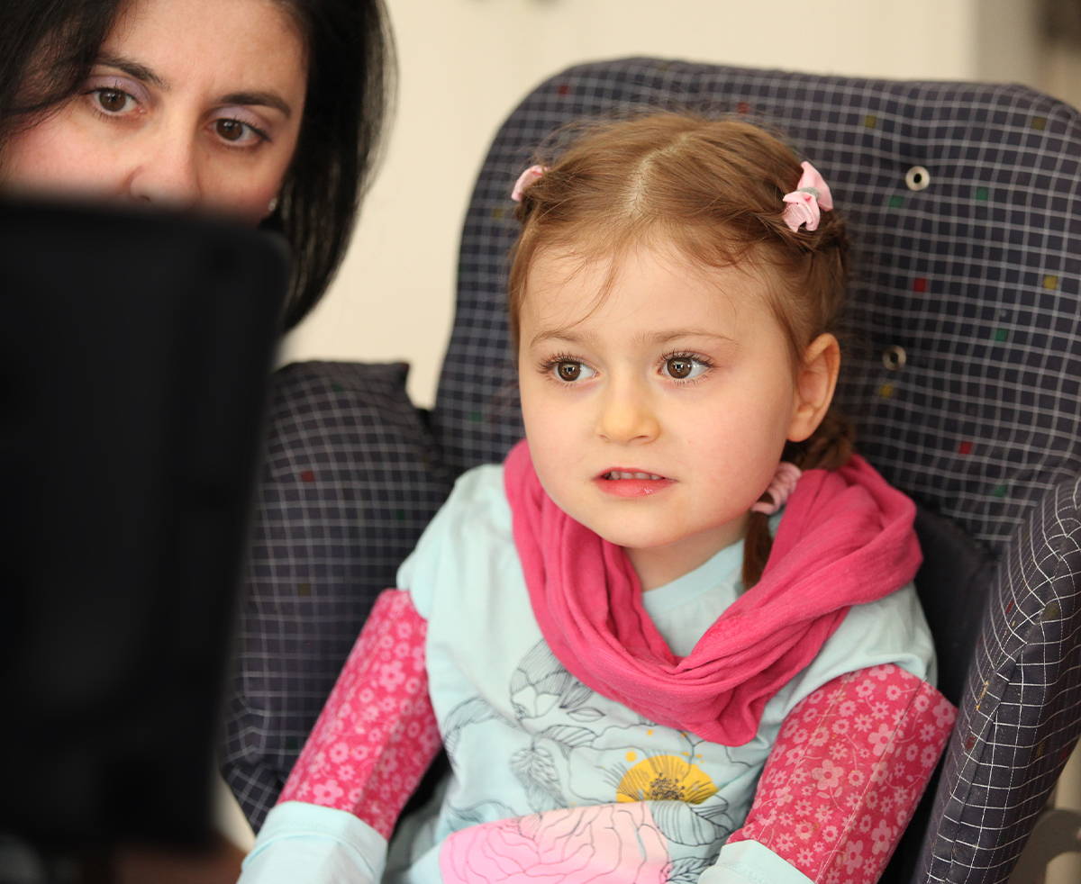  Ein junges Mädchen kommuniziert mit ihrer Mutter über ein Kommunikationsgerät mit Augensteuerung