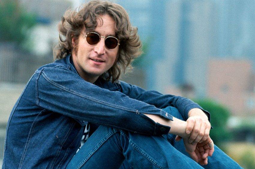 John Lennon portant des lunettes de soleil rondes et une tenue en jean