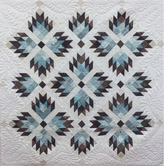 Quilt with a geometric pattern in shades of blue, black, and white.