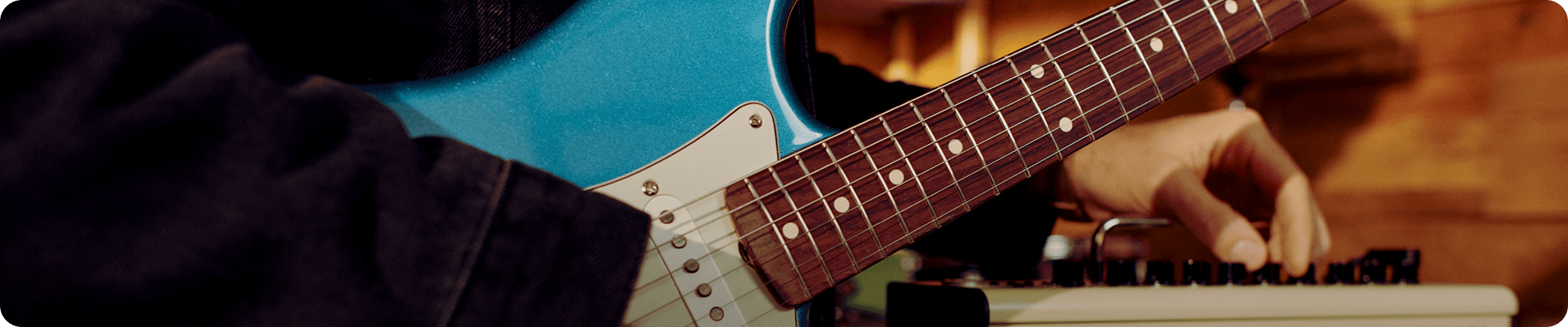 Person playing a blue electric guitar and using a keyboard.